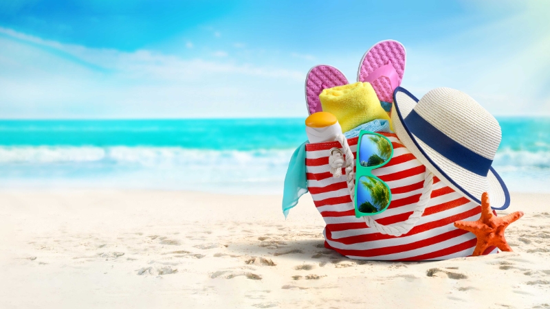 Bag at beach with sunglasses, hat and sun cream