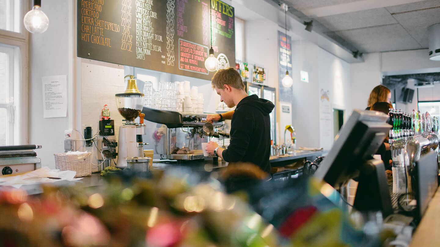 Barista working in coffee shop below the menu
