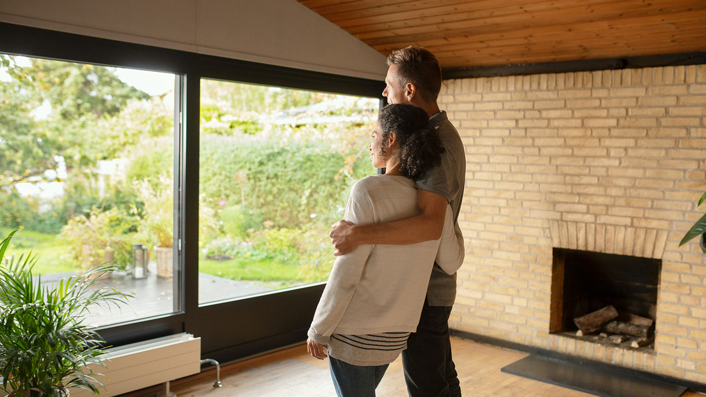 Couple with arms around eachother looking out window