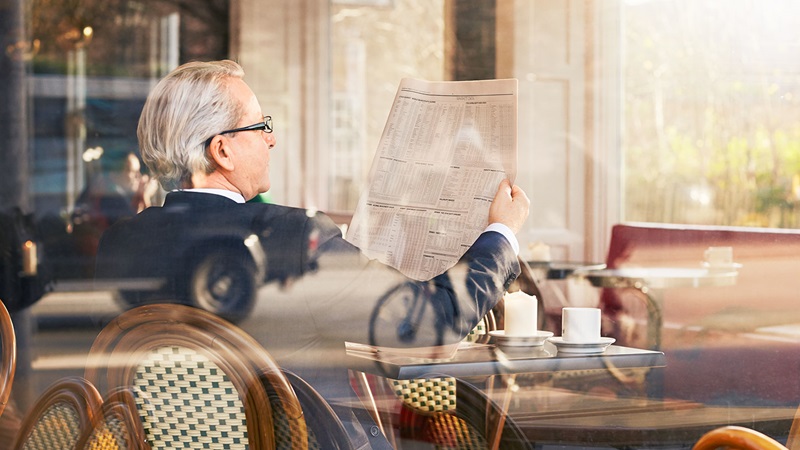 Older business man reading financial newspaper in cafe Older business man reading financial newspaper in cafe