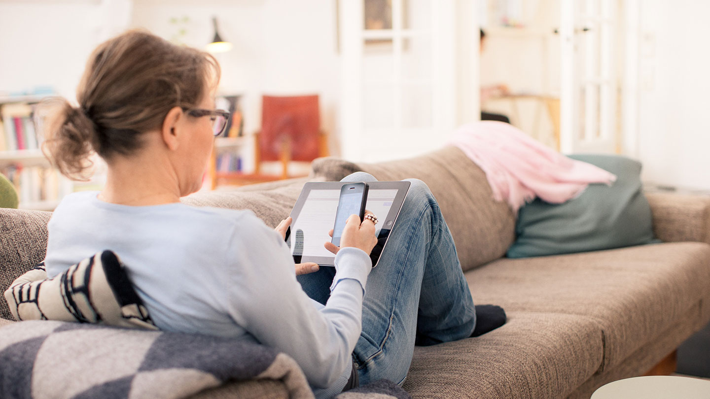 Woman on sofa with tablet and smartphone