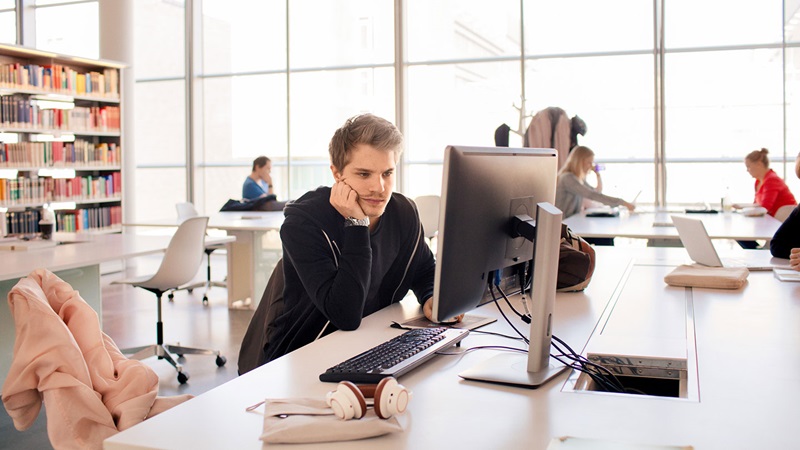 Male student using computer in library
