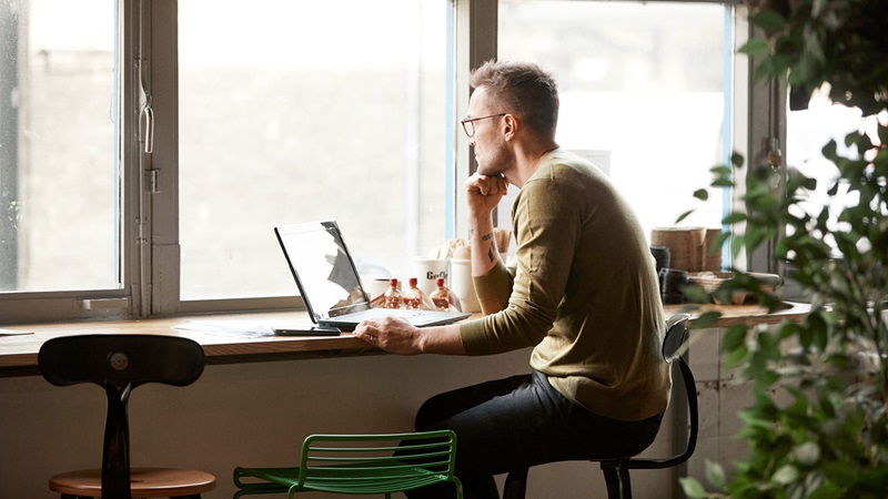 Man using laptop by window