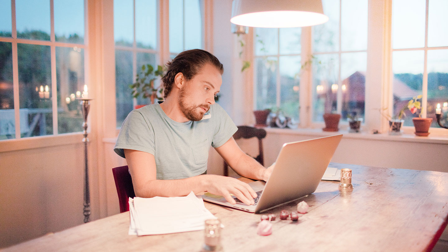 Man using phone and laptop while sitting at table