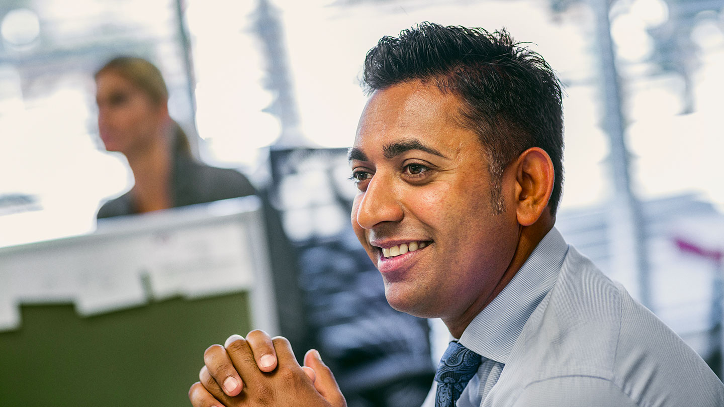 Man sitting in office with hands clasped together