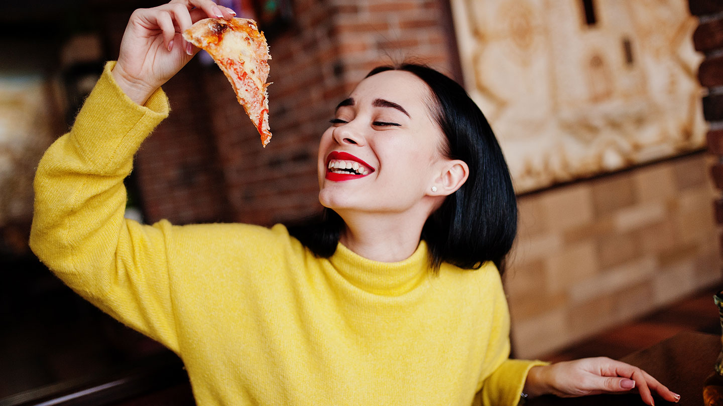 Lady smiling with a slice of pizza Lady smiling with a slice of pizza