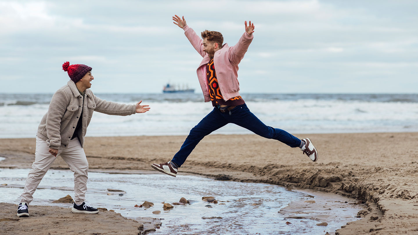 Man jumping across stream on beach