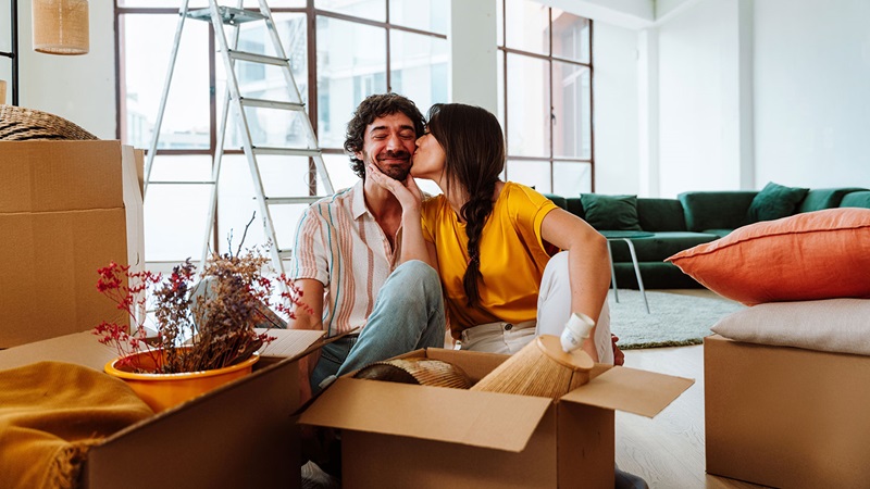 A couple sitting among moving boxes in a newly purchased home