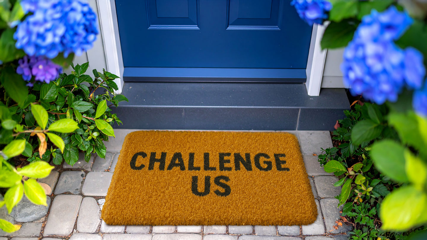 Blue door and brown doormat with the words Challenge Us 