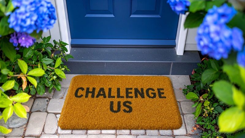 Blue door and brown doormat with the words Challenge Us