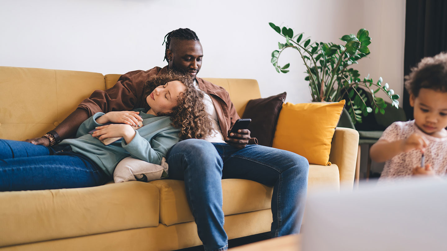 A family relaxing together on a cosy yellow sofa in their modern home, creating a warm and inviting atmosphere.
