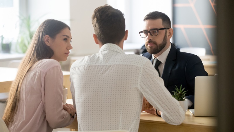 Couple sitting down at desk with an advisor Couple sitting down at desk with an advisor