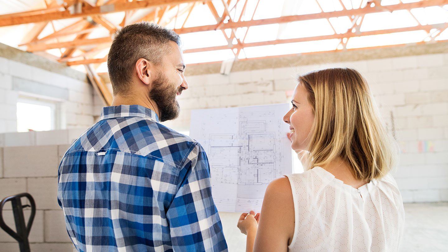 Couple looking at building plans for self buld home