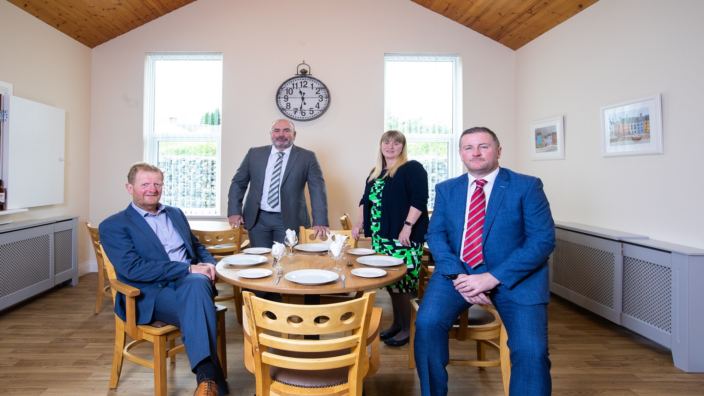 Four people inside sitting at a kitchen table.