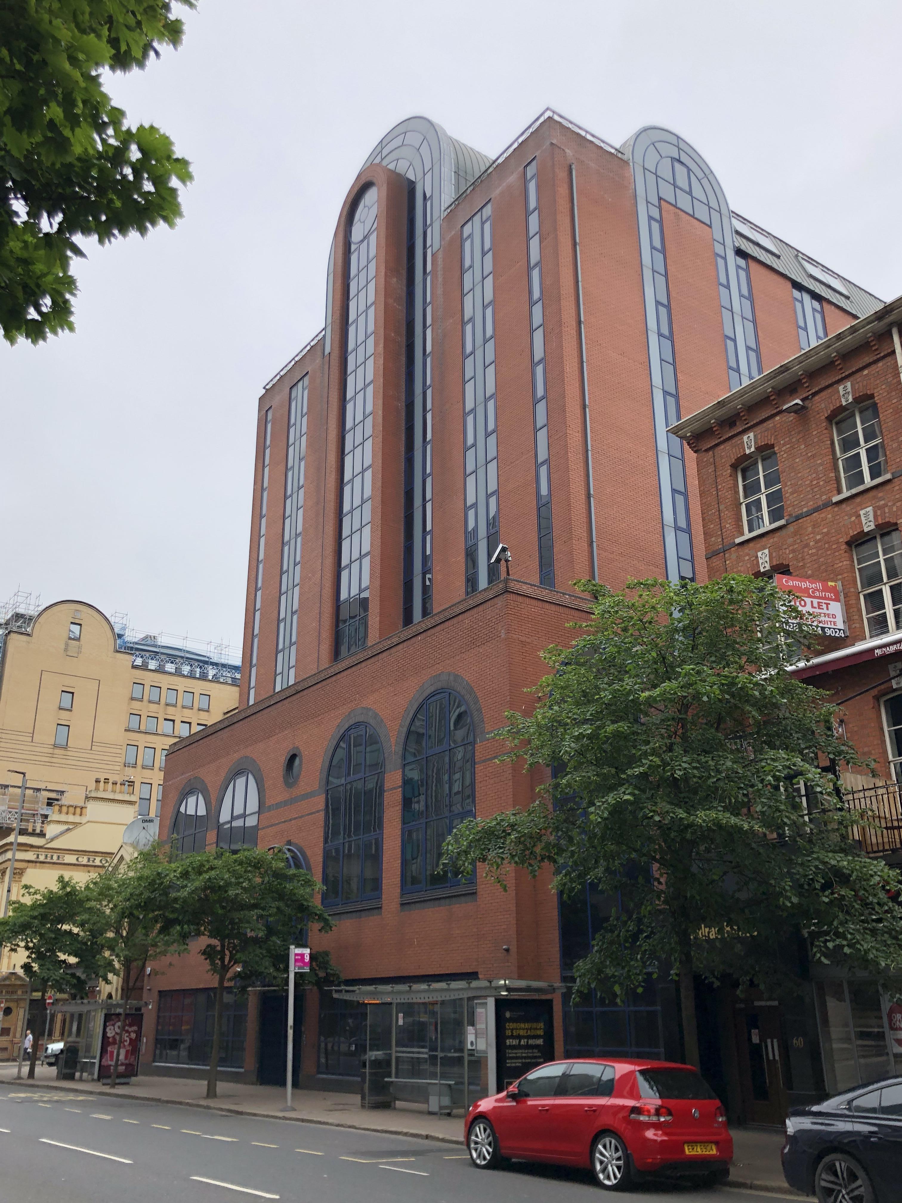 A large office building, with red bricks and long windows.