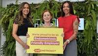 Endometriosis Friendly Employer "Three Danske colleagues smiling at the camera while holding a prop that says 'we're proud to be an endometriosis friendly employer'"