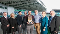 NI Environmental Benchmarking Survey 2023 Eight people stand together at an awards ceremony, the person in the middle holds onto an award.