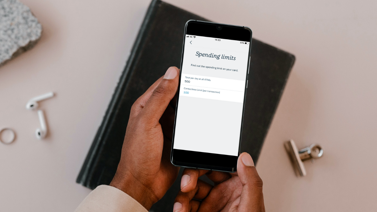 A hand holding a phone, the screen shows 'Spending limits'.