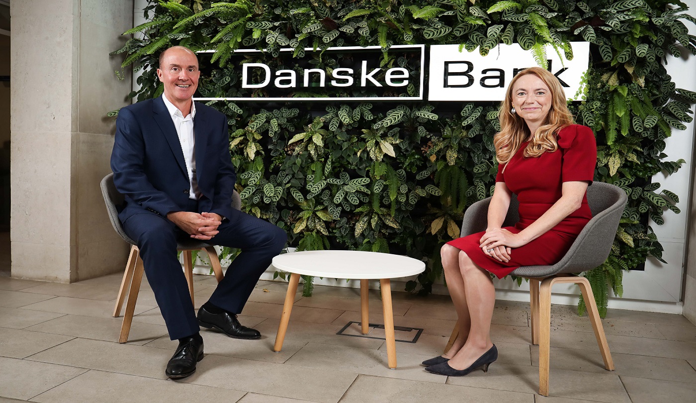 Danske Bank UK's new Chairman, Martin Stewart with Danske Bank UK's CEO, Vicky Davies.  Both are sitting in front of a living wall in a branch with the Danske Bank logo behind them.