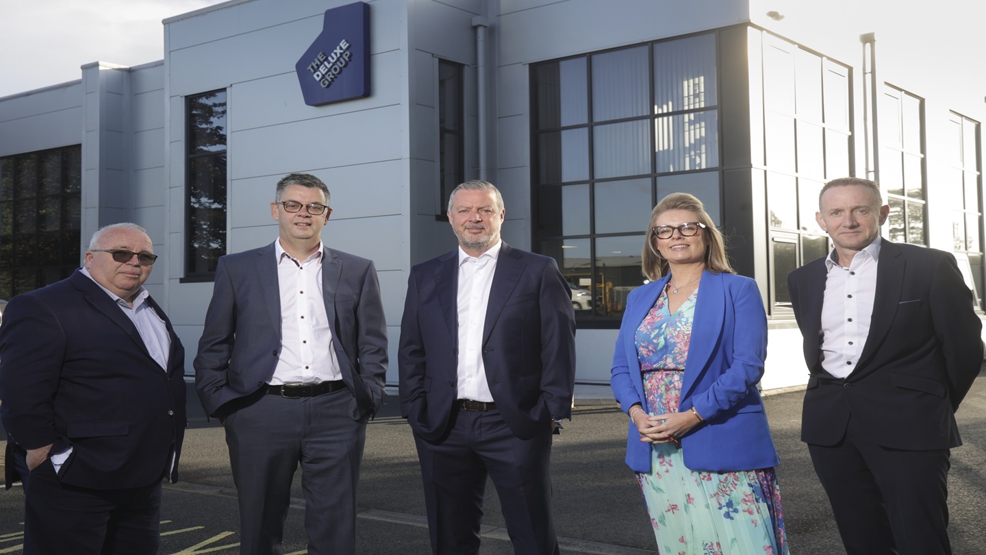Five people standing outside a The Deluxe Group building.