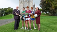 Three GAA players with the MacRory, MacLarnon and Mageean cups outside Armagh Cathedral. Representatives from Danske Bank and Ulster Schools GAA stand alongside them.