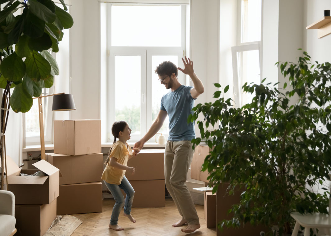 Father and daughter dancing in new home surrounded by boxes