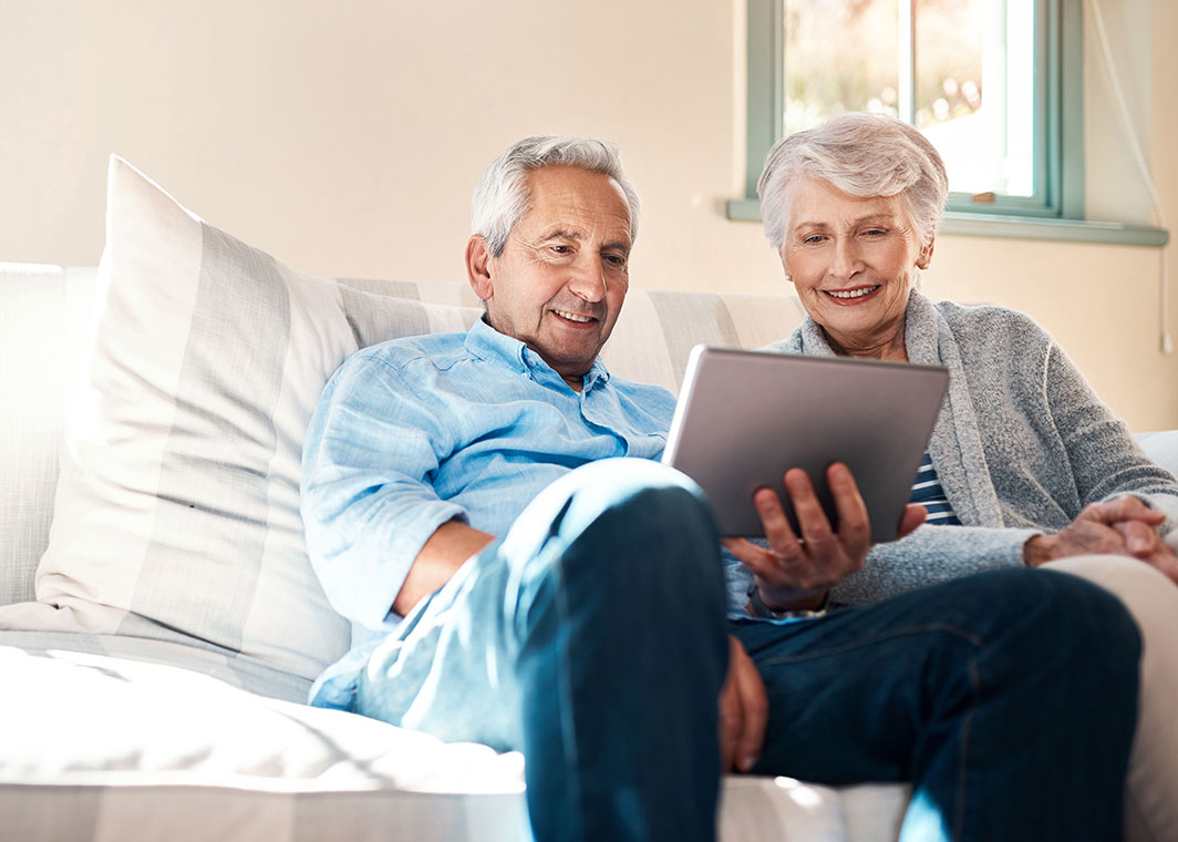 Happy older couple looking at tablet device