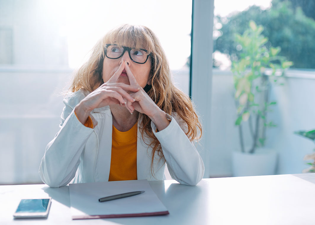 Lady sitting at desk with notepad and phone contemplating