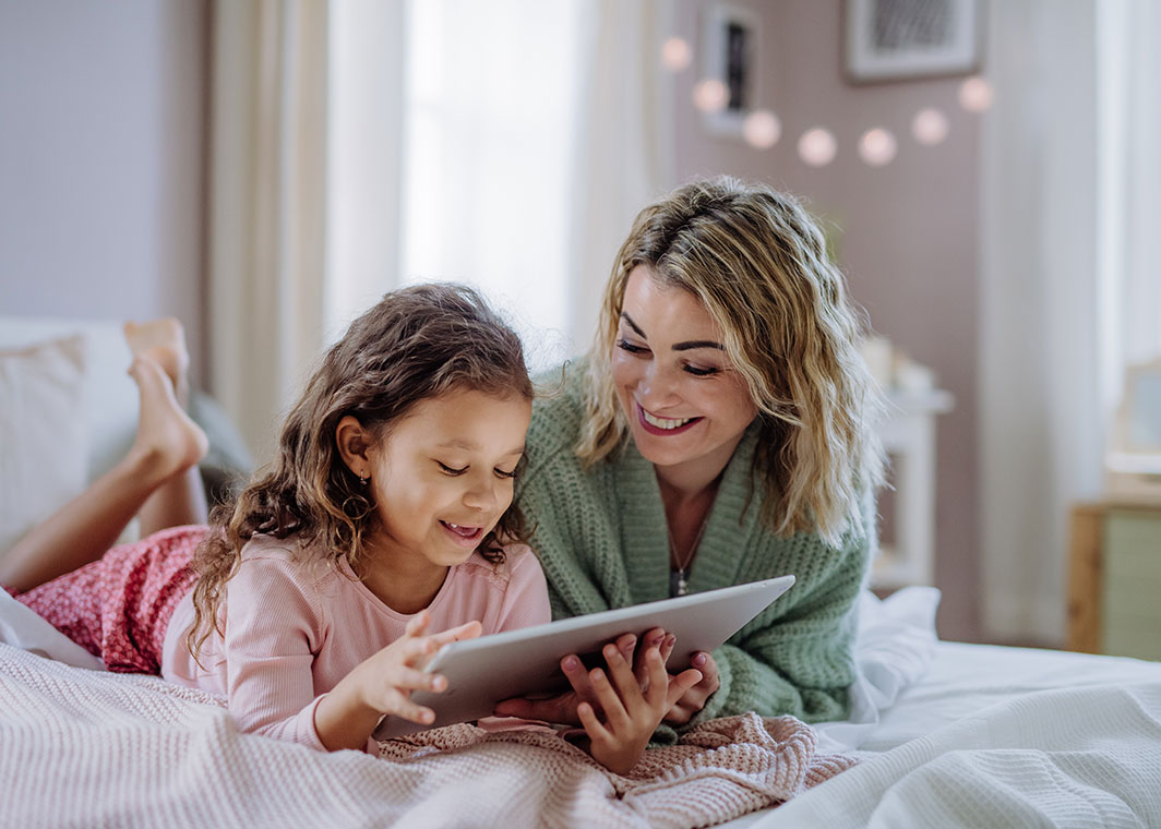 Mother and daughter smiling at tablet device