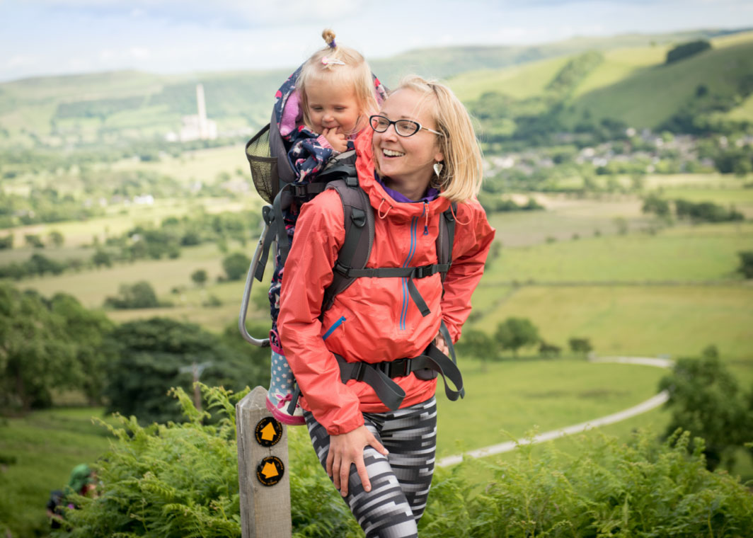 Mother hiking with young daughter on her back