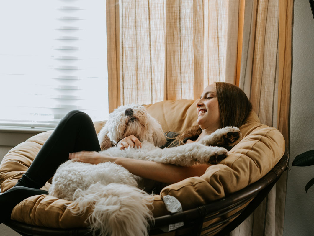 woman relaxing on comfrtable chair with dog in her lap